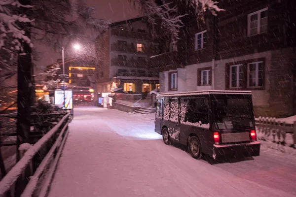 在寒冷的冬夜 在无汽车的阿尔卑斯山山村的雪街上乘坐电动出租车 — 图库照片