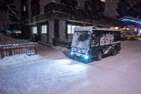 在寒冷的冬夜 在无汽车的阿尔卑斯山山村的雪街上乘坐电动出租车 — 图库照片