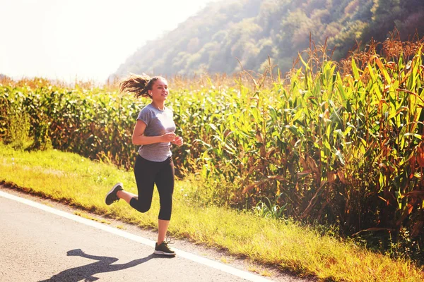 年轻妇女享受健康的生活方式 而慢跑沿乡间小路 — 图库照片