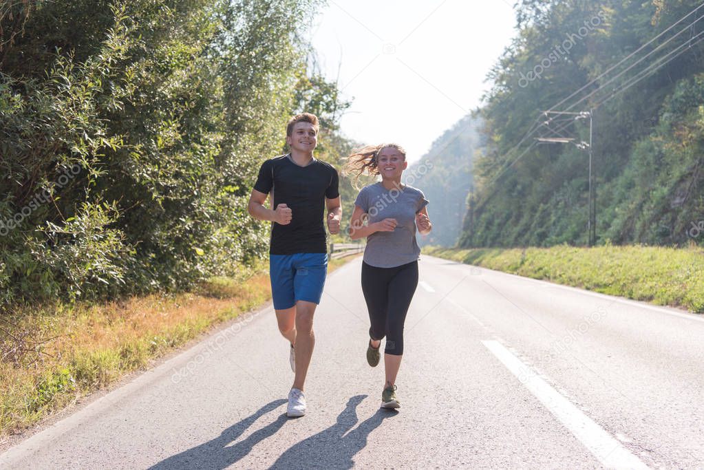 young couple enjoying healthy lifestyle while jogging along country road