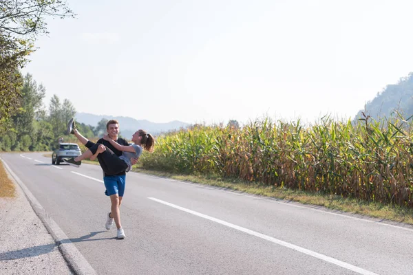国の道路 フィットネスの概念に沿ってジョギング中彼の腕で女性を運ぶ男 — ストック写真
