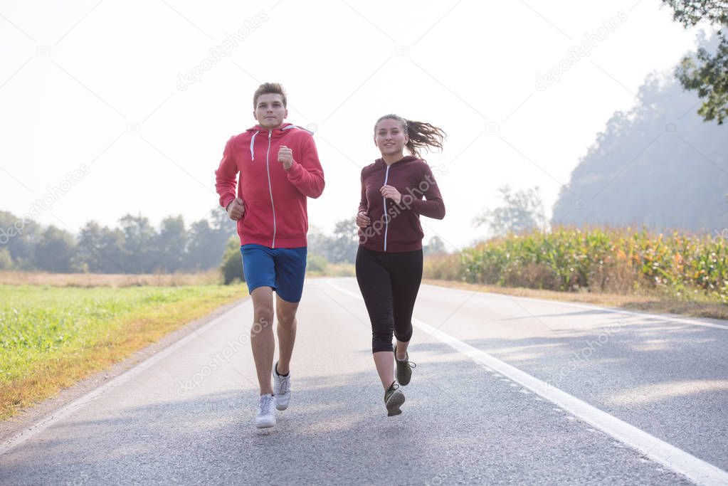 young couple enjoying healthy lifestyle while jogging along country road