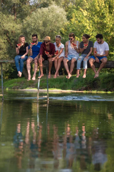 Gruppe Junger Freunde Genießt Wassermelone Während Sie Auf Der Holzbrücke — Stockfoto