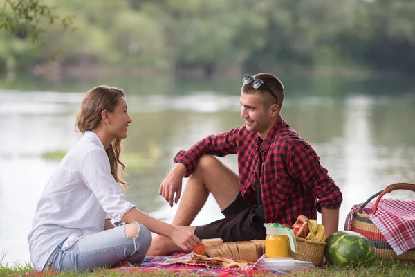 情侣在爱享受野餐时间和食物在美丽的自然河岸边 — 图库照片