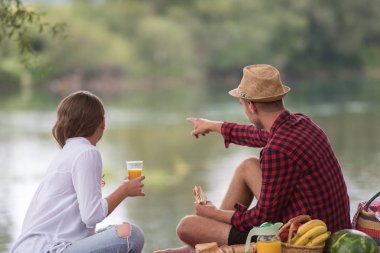 Piknik zamanı içki ve nehir kıyısında güzel doğada yiyecek zevk aşık çift
