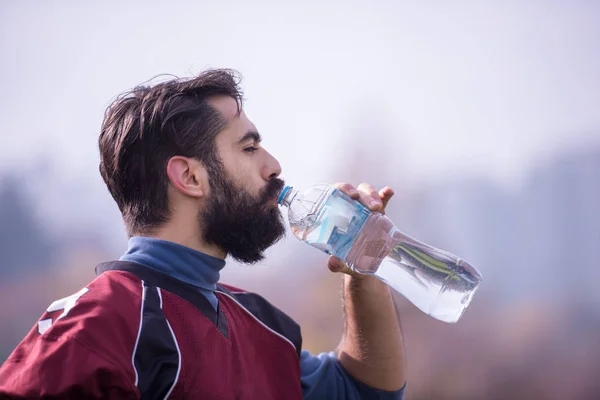 Zmęczony Amerykański Piłkarz Pijący Wodę Podczas Odpoczynku Ciężkim Treningu Boisku — Zdjęcie stockowe