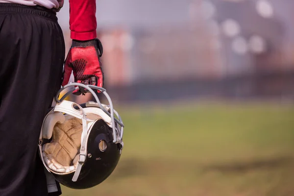 フィールドで黒いヘルメットを保持しているアメリカン フットボール選手のクローズ アップ ショット — ストック写真