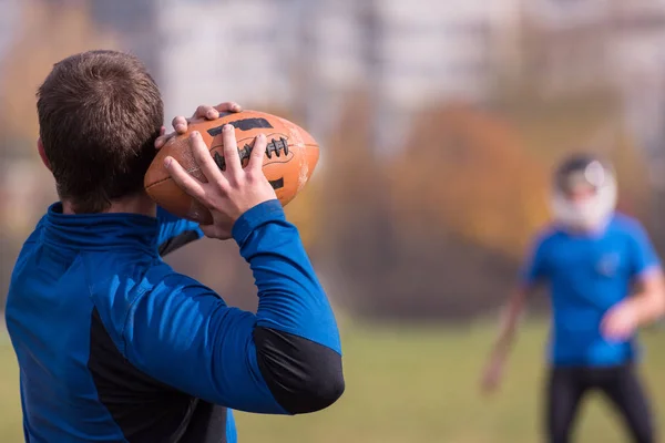 チーム監督はフィールドでのトレーニング中にアクションで若いアメリカのサッカー選手のグループにボールを投げます — ストック写真