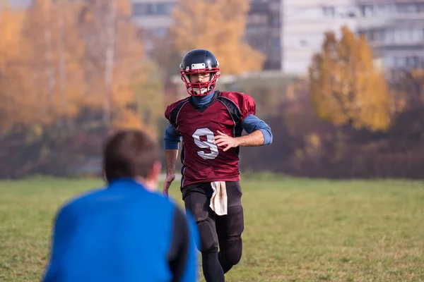 チーム監督はフィールドでのトレーニング中にアクションで若いアメリカのサッカー選手のグループにボールを投げます — ストック写真