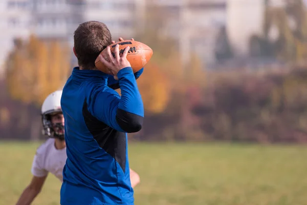 チーム監督はフィールドでのトレーニング中にアクションで若いアメリカのサッカー選手のグループにボールを投げます — ストック写真