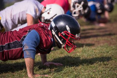 Amerikan futbol takımı sahada antrenman yaparken şınav çekiyor.