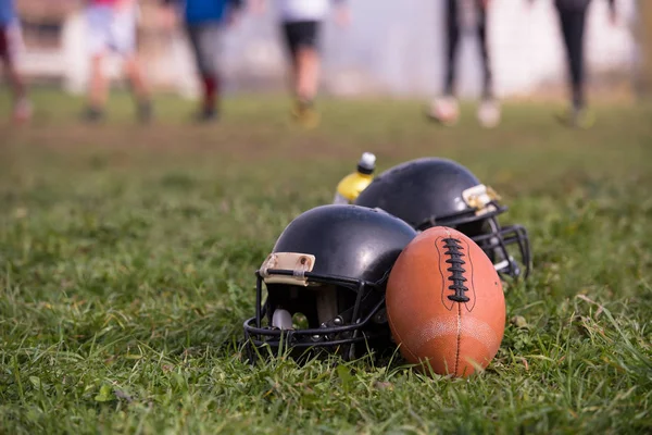 アメリカン フットボールのヘルメットとボールがフィールドの上に横たわる — ストック写真