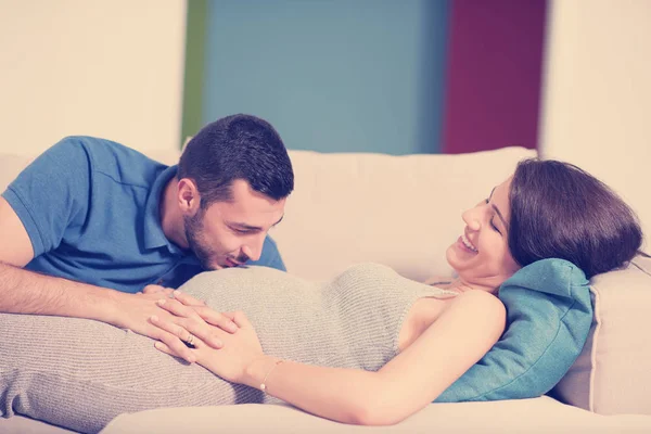 自宅のソファでリラックスしながら妊娠中の妻の腹を聞いて将来の幸せのお父さん — ストック写真