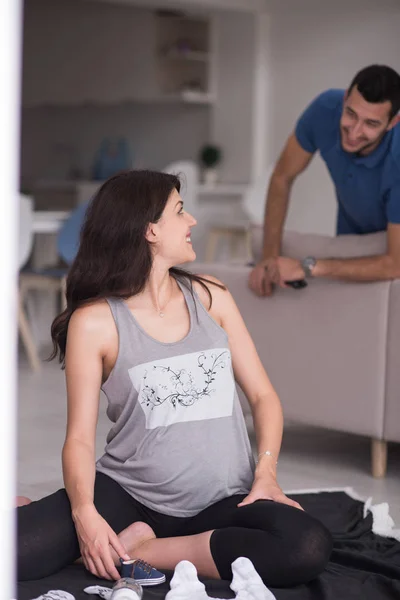 一对幸福的孕妇在地板上检查他们未出生的孩子的清单 — 图库照片