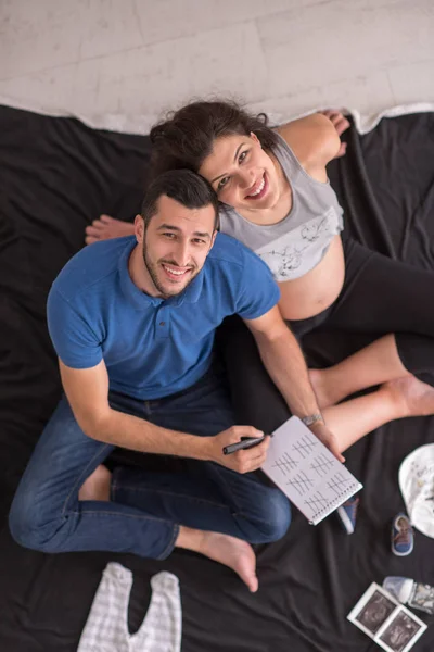 Bovenaanzicht Van Een Gelukkige Zwangere Paar Controleren Een Lijst Van — Stockfoto