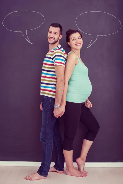 妊娠中の若いカップルを考える彼らのやがて生まれる赤ん坊の名前と黒い黒板に書いて — ストック写真