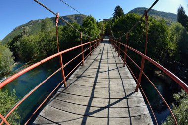 Yaz aylarında güzel doğada vahşi nehir üzerinde kırmızı ahşap köprü