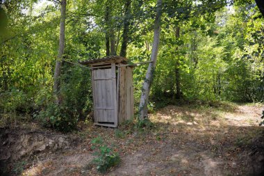 old wooden retro outdoor toilet in forest clipart
