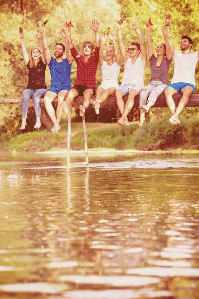 Grupo Jóvenes Amigos Disfrutando Sandía Mientras Están Sentados Puente Madera —  Fotos de Stock