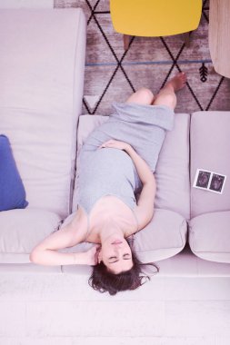 Genç bir hamile kadının koltukta evde dinlenirken bebeğin ultrason fotoğraf arıyor üstten görünüm