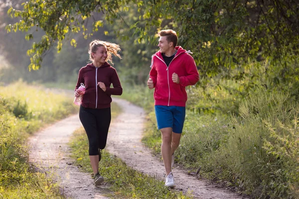 年轻夫妇一边在乡间小径上慢跑一边享受健康的生活方式 运动和健身的概念 — 图库照片