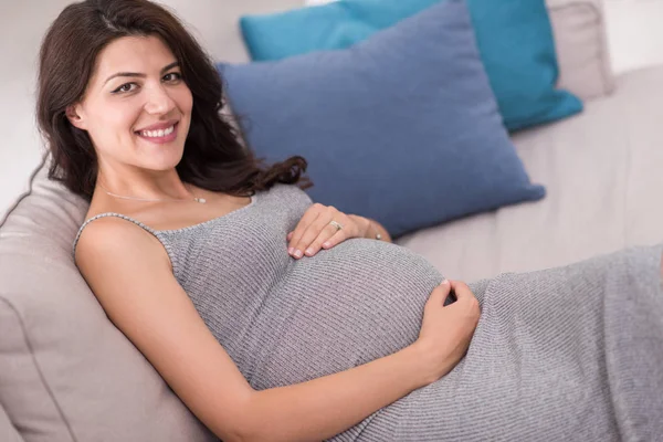 Genç Mutlu Hamile Kadın Evde Kanepede Otururken Karın Tutmak — Stok fotoğraf