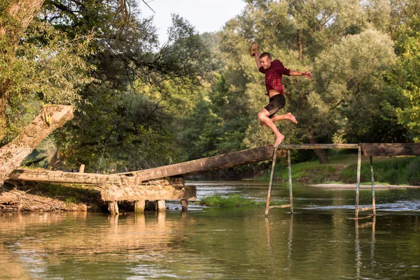 快乐的男人穿着衣服跳进河里 — 图库照片