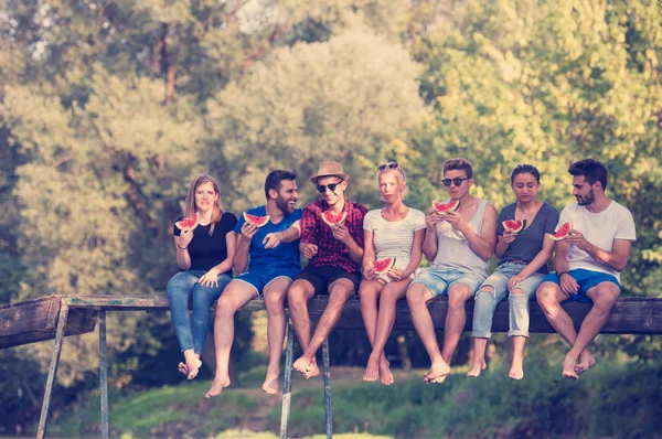 Grupo Jóvenes Amigos Disfrutando Sandía Mientras Están Sentados Puente Madera — Foto de Stock