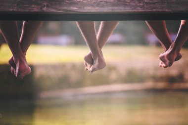 Grup ahşap köprü Nehri üzerinde asılı bacaklar odaklanarak oturan insan