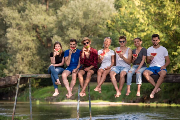 Gruppe Junger Freunde Genießt Wassermelone Während Sie Auf Der Holzbrücke — Stockfoto