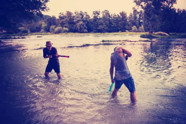 Gün Batımında Nehirde Birbirlerine Tabancasıyla Sıçratarak Eğlenen Genç Adamlar — Stok fotoğraf