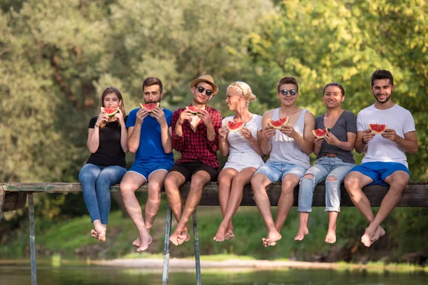 Grupo Jóvenes Amigos Disfrutando Sandía Mientras Están Sentados Puente Madera —  Fotos de Stock