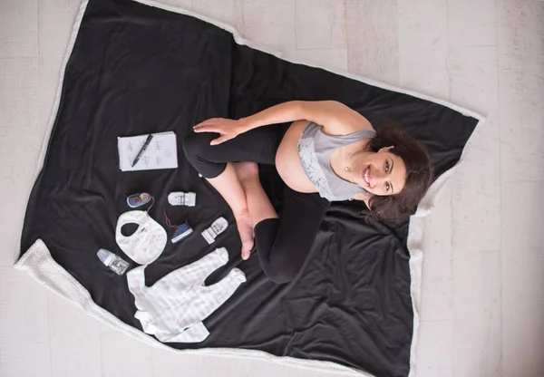 Μια Έγκυος Γυναίκα Στο Σπίτι Στο Πάτωμα Ελέγχοντας Λίστα Ρούχα — Φωτογραφία Αρχείου