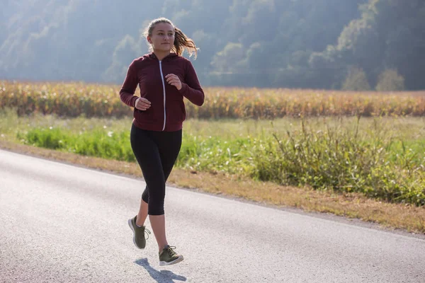 国の道路 フィットネスの概念に沿ってジョギングしながら健康的なライフ スタイルで楽しむ若い女性 — ストック写真