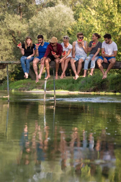 Gruppe Junger Freunde Genießt Wassermelone Während Sie Auf Der Holzbrücke — Stockfoto