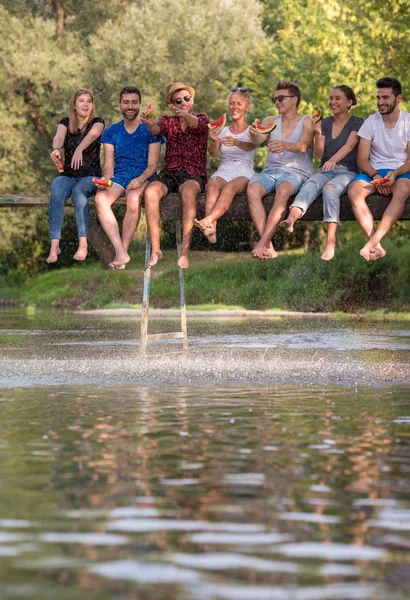 Ryhmä Nuoria Ystäviä Nauttivat Vesimeloni Istuessaan Puinen Silta Joen Yli — kuvapankkivalokuva