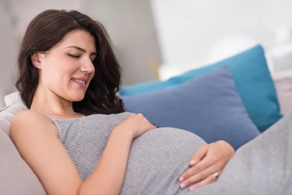 Joven Feliz Embarazada Mantener Mano Vientre Mientras Está Sentado Sofá — Foto de Stock