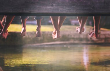 Grup ahşap köprü Nehri üzerinde asılı bacaklar odaklanarak oturan insan