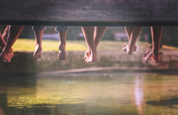 Группа Людей Сидящих Деревянном Мосту Через Реку Акцентом Висящие Ноги — стоковое фото