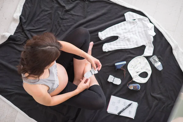 Μια Έγκυος Γυναίκα Στο Σπίτι Στο Πάτωμα Ελέγχοντας Λίστα Ρούχα — Φωτογραφία Αρχείου