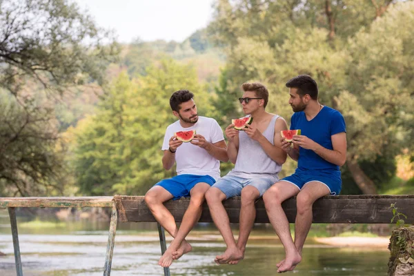 Gruppe Junger Männer Genießt Wassermelone Während Sie Auf Der Holzbrücke — Stockfoto