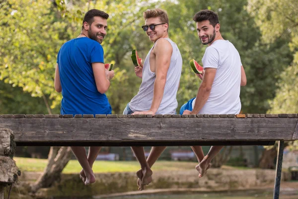 Grupo Jovens Que Gostam Melancia Enquanto Sentado Ponte Madeira Sobre — Fotografia de Stock