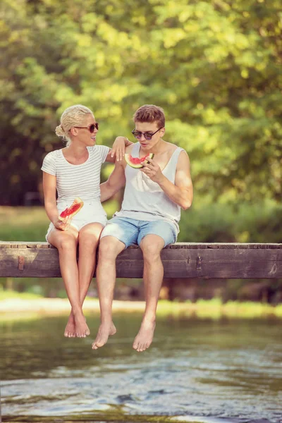 Pareja Enamorada Disfrutando Sandía Mientras Sienta Puente Madera Sobre Río —  Fotos de Stock