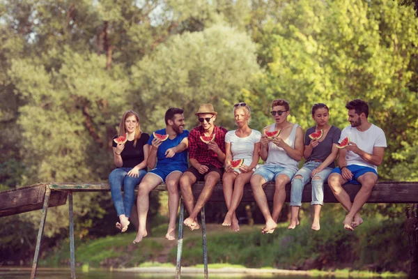 Grupo Jóvenes Amigos Disfrutando Sandía Mientras Están Sentados Puente Madera — Foto de Stock