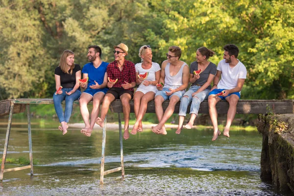 Grupp Unga Vänner Njuter Vattenmelon Medan Sitter Träbro Över Floden — Stockfoto