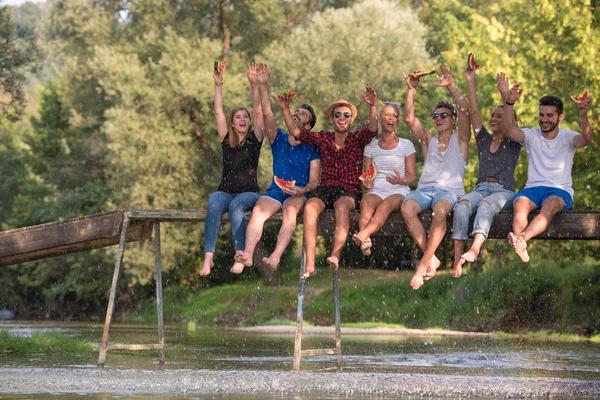 Grupa Młodych Przyjaciół Ciesząc Się Arbuz Siedząc Drewniany Most Nad — Zdjęcie stockowe