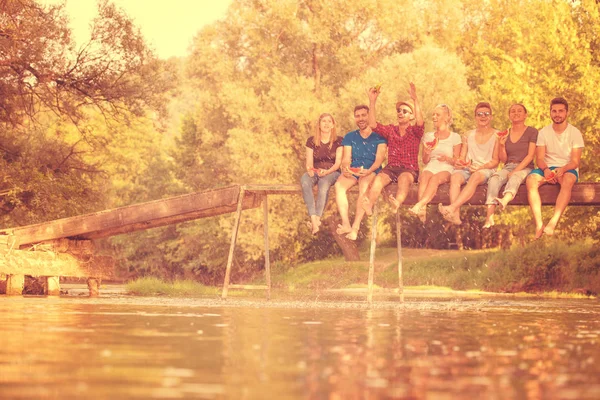 Grupo Jóvenes Amigos Disfrutando Sandía Mientras Están Sentados Puente Madera —  Fotos de Stock