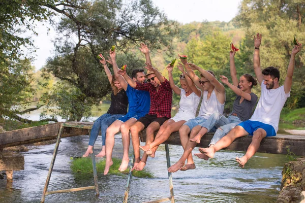 Grupo Jóvenes Amigos Disfrutando Sandía Mientras Están Sentados Puente Madera — Foto de Stock