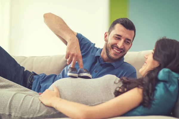 快乐怀孕夫妇放松在沙发沙发在家里 — 图库照片