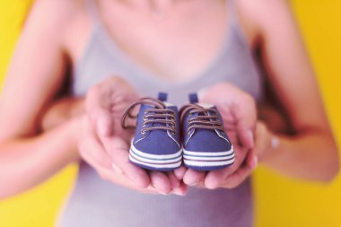 Yeni doğan bebek patiği izole sarı arka plan, Aile ve ebeveynlik kavramı üzerinde tutan genç hamile Çift
